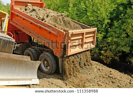 A 10 yard dump truck dumps its load of rock and soil on a new road construction project