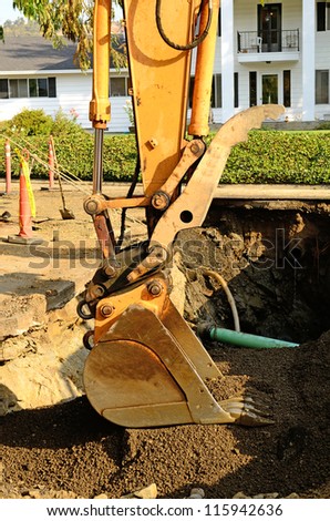 a large track hoe excavator at the repair work following a broken water main leak from a fire hydrant base,