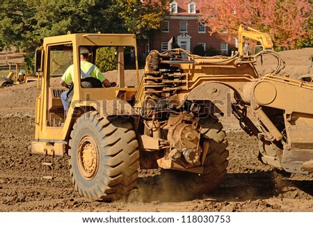 Large construction scraper moving soil for a new commercial housing development