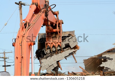 A track hoe excavator using its claw thumb to tear down an old hotel to make way for a new commercial development