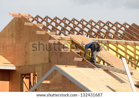 Construction crew working on the roof sheeting and outriggers or ladder of a new, two story, commercial apartment building in Oregon