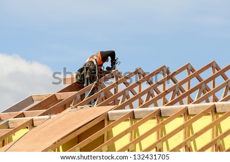 Construction crew working on the roof sheeting and outriggers or ladder of a new, two story, commercial apartment building in Oregon