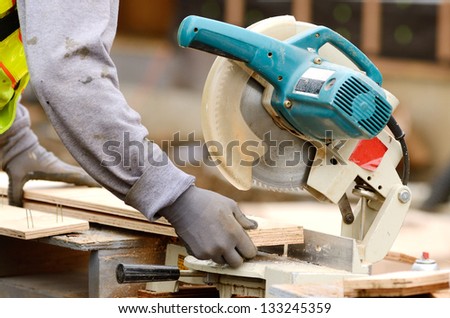 Worker using a electric compound cut off saw at a large commercial housing development in Oregon