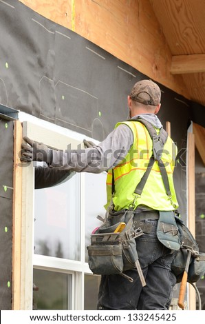 Worker Installing Trim Around A Window Prior To Putting On Siding At A Large Commercial Housing Development In Oregon