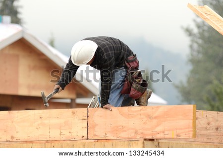 Worker installing a second floor wood joist at a large commercial housing development in Oregon