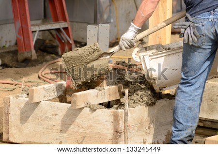 Worker working concrete on a post foundation support at a large commercial housing development in Oregon