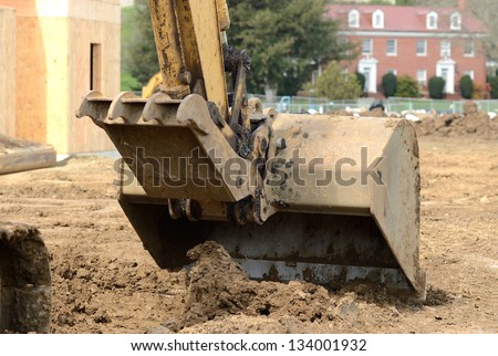Construction contractor using a small track hoe excavator to dig a water line trench on a new commercial residential development