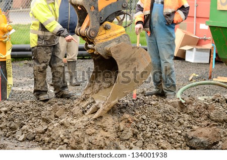 Worker using a small tracked excavator to dig a hole to fix a water leak at a large commercial housing development in Oregon