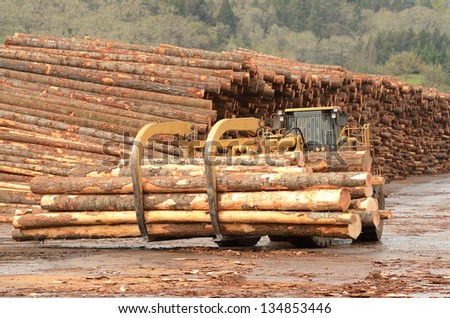 large wheeled front end log loader working the log yard at a lumber processing mill that specializes in small logs