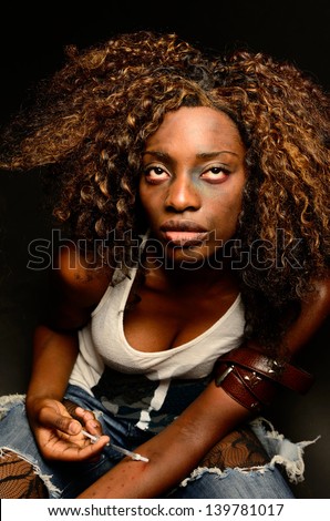 A young beautiful african american female poses as a track whore shooting up narcotics in this dark photo shoot against black