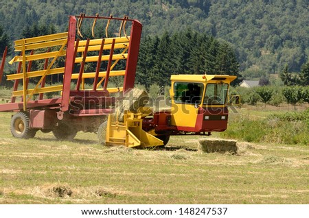 Self contained hay bale wagon picking up bales of alfalfa from a farm field