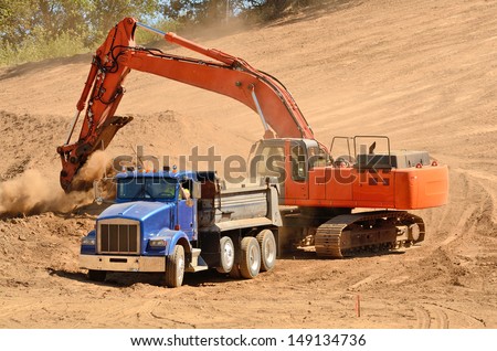 Track hoe excavator filling up a dump truck at  a new commercial construction development