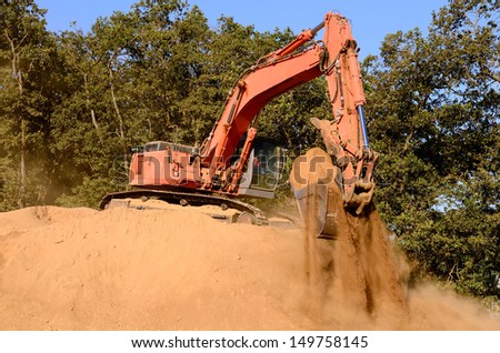 Large track hoe excavator working on large dirt pile on a new commercial development construction project.