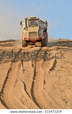 A large articulated dump truck moves top soil pile for later use on a new commercial construction development project