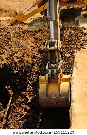 A backhoe and crew dig a utility trench for gas and other electrical utilities at a new commercial construction development
