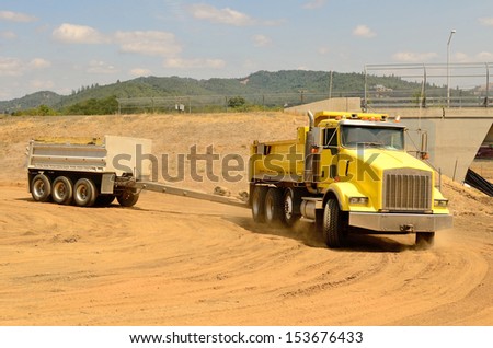 Tandem dump truck arrives at a new commercial construction development project for its load of dirt