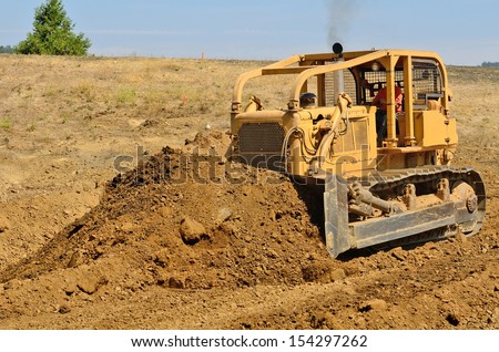 Large bulldozer moving rock and soil for a fill lift at a new commercial development road construction project