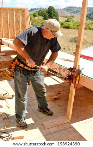 Building contractor worker using a wall jack to raise a wall for the second floor on a new home construction project
