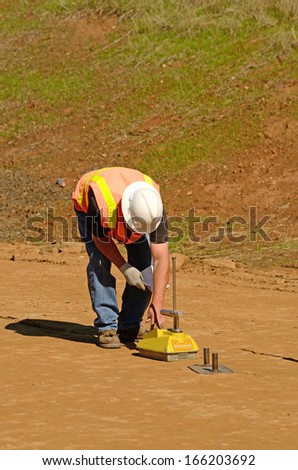 Field engineer using a Nuclear Density Gauge to check for soil density of a soil lift fill on a new commercial development construction project