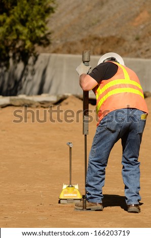 Field engineer using a Nuclear Density Gauge to check for soil density of a soil lift fill on a new commercial development construction project