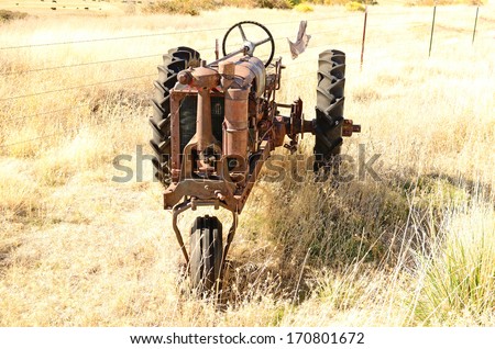 An old three wheel tractor sits next to a large cattle ranch in northern California