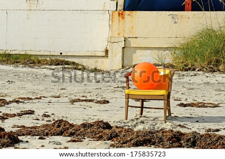 Orange beach ball sitting in a chair on Daytona Beach Florida