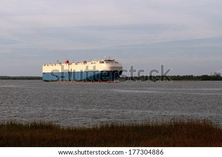A large ship or barge built specifically for transporting automobiles leaves port near Brunswick Georgia