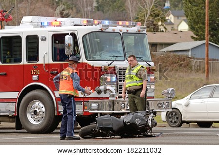 ROSEBURG, OR, USA - JANUARY 13, 2014:  Emergency responders at the scene of a motorcycle vs car at a busy intersection that left the rider with serious injuries.