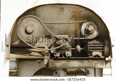 An electric motor moves several gears and chain on industrial equipment