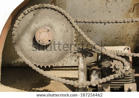 An electric motor moves several gears and chain on industrial equipment