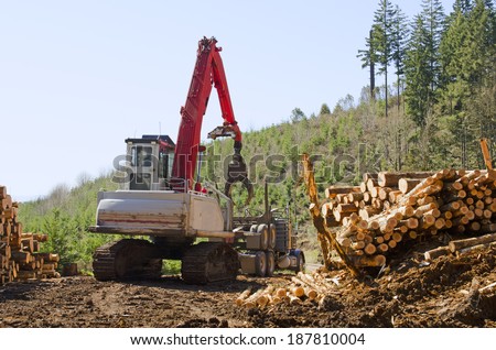 Track loader unloading the rear trailer from a log truck prior to loading at a logging site in Oregon