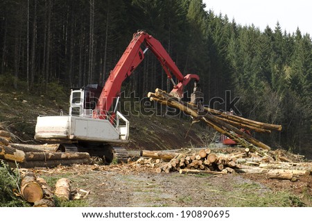 A log loader or forestry machine moves fresh cut logs for loading on a log truck at the site logging landing in southern Oregon