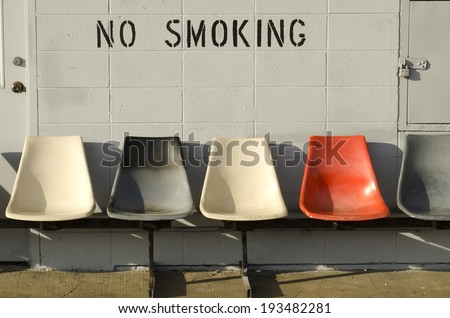 No smoking siting area outside a bus station with cigarette butts under chairs