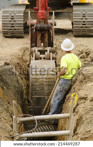 Construction workers using trench shoring equipment to backfill and install deep utilities at a new commercial  development