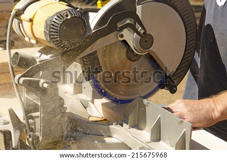 Framing contractor using a circular cut off  saw to trim wood studs to length.