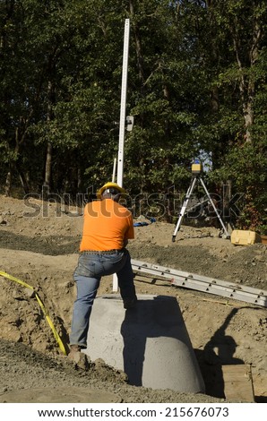 Construction excavation contractor uses a level rod and laser to install a concrete sewer vault structure