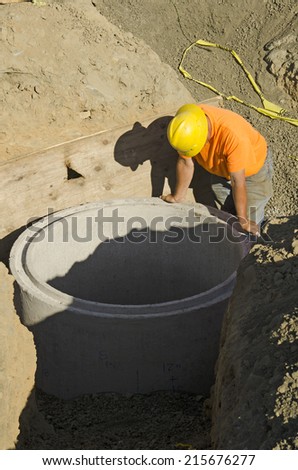 Excavation contractor installing a riser on a manhole vault on a sanitary sewer system on a new commercial development