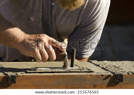 Concrete contractor using a concrete trowel to  finish top of the foundation of a custom luxury home