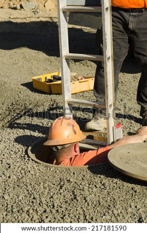 Excavation contractor entering a manhole while working on sanitary sewer system on a new commercial development