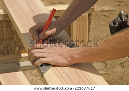 Building construction contractor carpenter measuring a wood wall stud with a tape measure