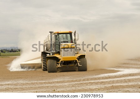 Agricultural lime being spread by a big tired truck or tractor  on a newly plowed farm field