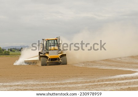 Agricultural lime being spread by a big tired truck or tractor  on a newly plowed farm field