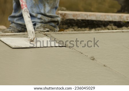 Concrete construction contractor using a edger tool on a sidewalk, curb and storm drainage gutter on a new urban road street project