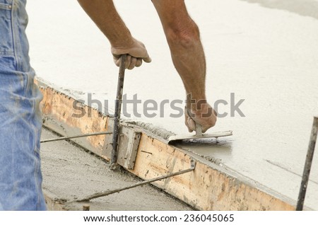 Concrete construction contractor using a edger tool on a sidewalk, curb and storm drainage gutter on a new urban road street project