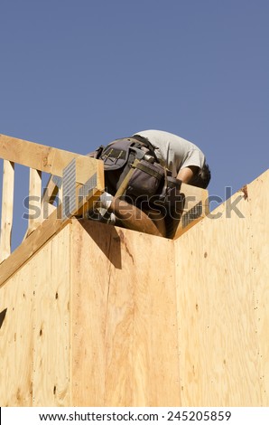 Building contractor carpenter placing new home wood engineered trusses on a residential construction site