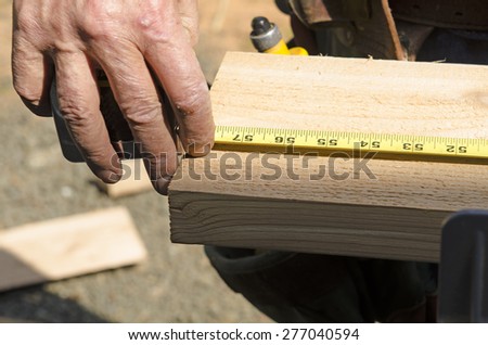 Wood siding contractor using a tape measure before cutting trim boards on the construction of a new home
