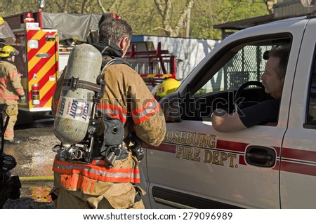 Roseburg OR, USA - March 26, 2014: Fire incident commander fire chief discussing operations with firefighters on a structure fire of a mobile home