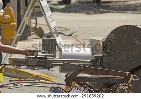 Using a hydraulic hole saw to cut in a large pipe into concrete new water line project with diamond bit or saw
