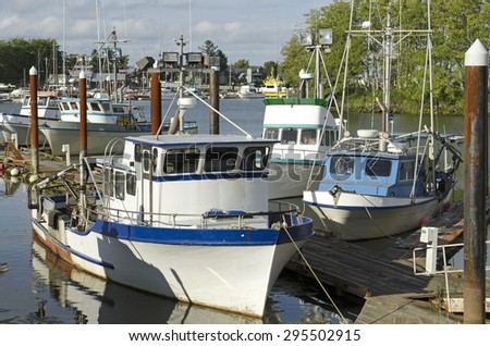 Small boat fishing fleet sits at dock in marina in the Astoria, Warrenton, and Harbor Oregon area on a light cloudy sunny summer day