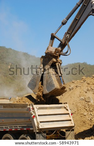 Clamshell bucket loader working a spoil pile on a hill removal project in Roseburg Oregon